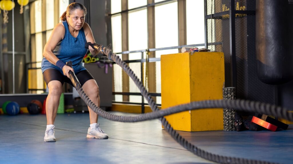 Older woman using battle ropes at Crossfit gym fitness IndianFaces Shutterstock