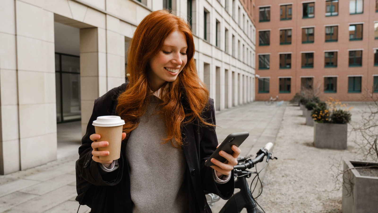 Young redheaded woman on phone with bike and coffee Dean Drobot Shutterstock Young redheaded woman on phone with bike and coffee Dean Drobot Shutterstock